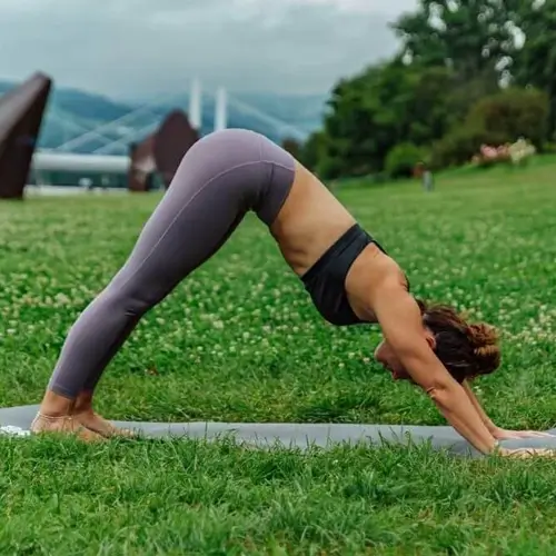 girl practicing adho mukha svanasana in garden